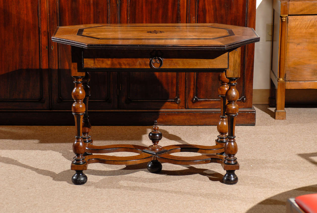A Louis XIII style walnut table with octagonal top, parquetry inlay, drawer and cross stretcher. 