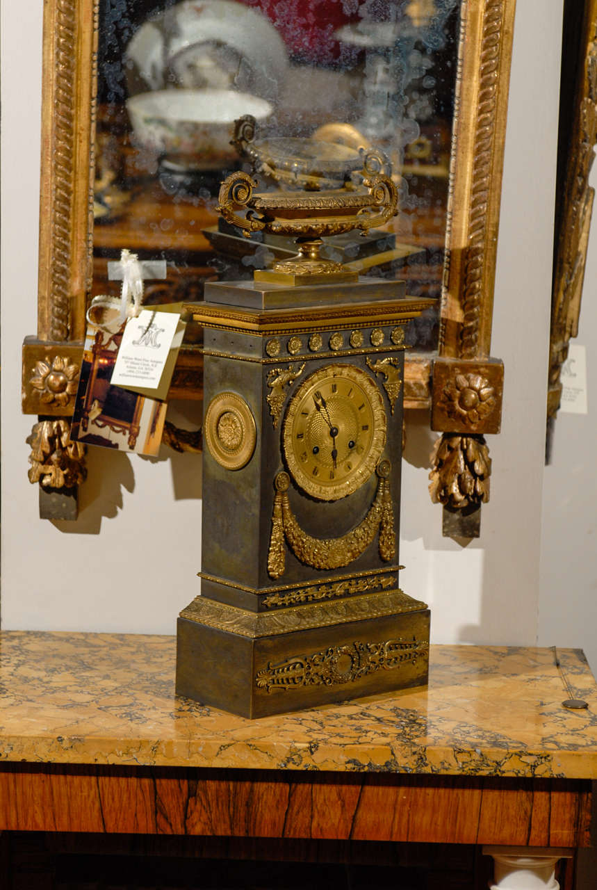 A large Neoclassical mantle clock in brass with ormalu mounts, urn and swag detail. 

William Word Fine Antiques: Atlanta's source for antique interiors since 1956.