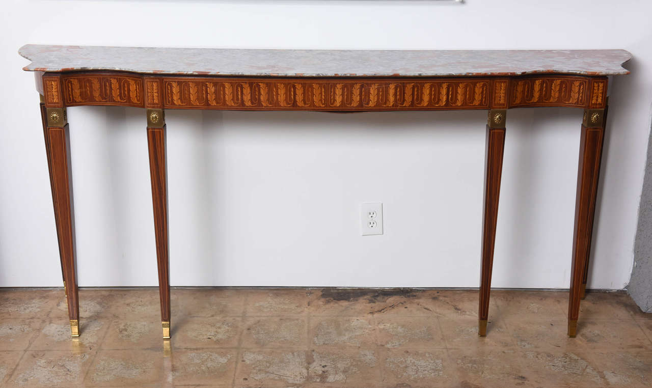 The marble top above a finely inlaid frieze with acanthus and foliate, the square tapering legs with Fine bronze mounts with stars and sabots, the legs with line inlay.