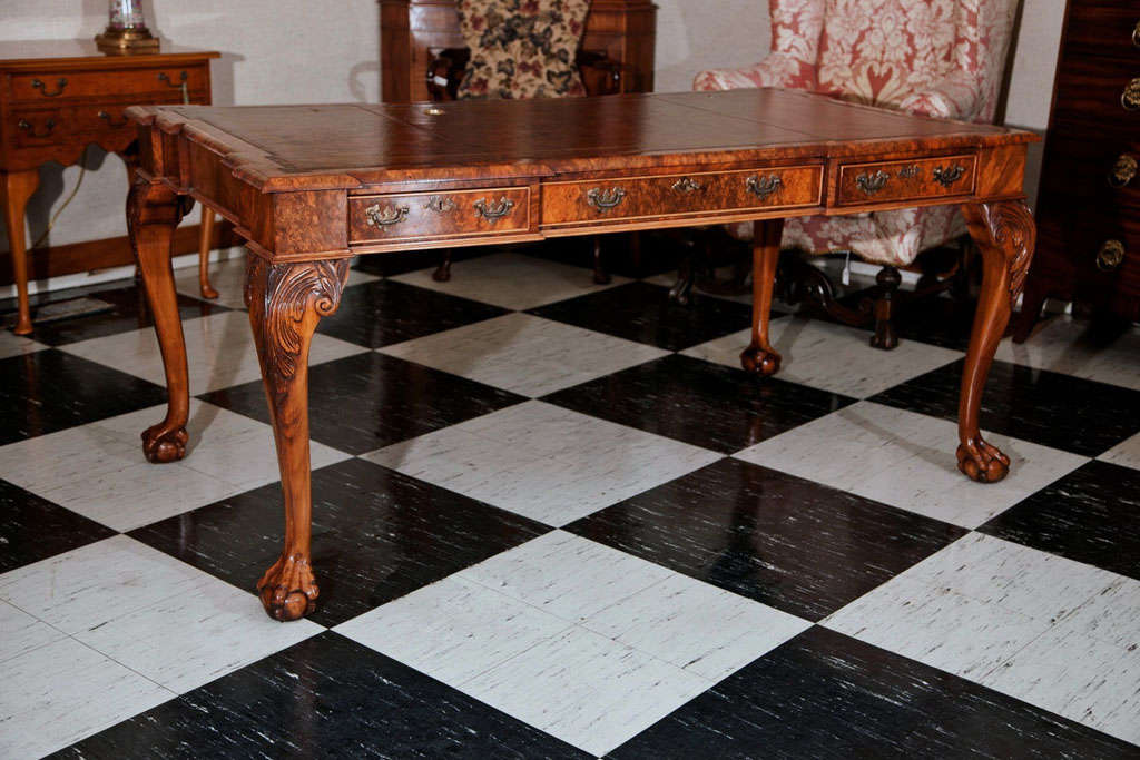 This beautiful George II style executive writing table/desk in burled walnut features a uniquely shaped top, cabriole legs with acanthus carved knees and deeply carved claw and ball feet. Its handsome antique appearance is augmented by 21st century