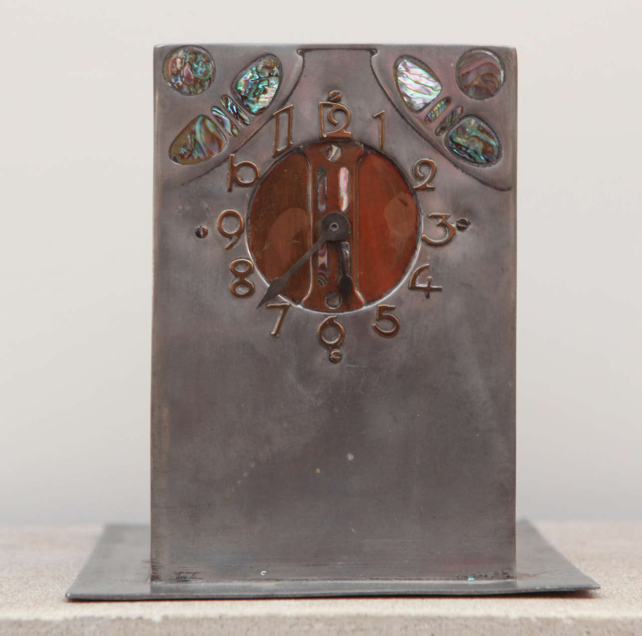 Liberty & Co. hand-wrought pewter, copper and abalone clock, British, circa 1905.

Original wind-up key included. Clock is in working condition.