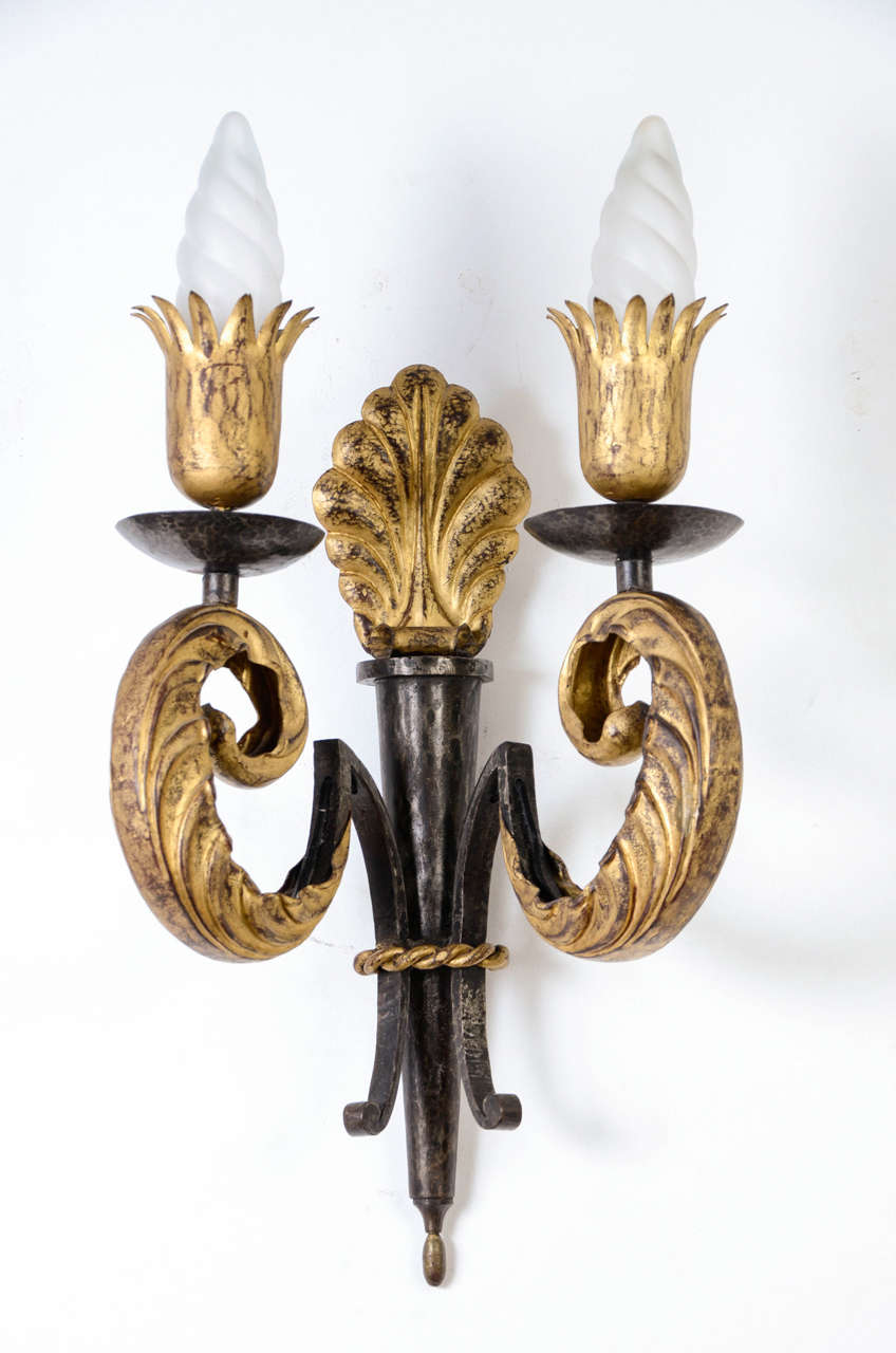 Important pair of wall-sconces, circa 1945, by Gilbert Poillerat (1902-1988).

Black and gilt patinated forged iron structure, with two acanthus scroll light arms, palm base and crowned cups bobeches.

Height with bulbs: 55 cm.

Ref: F.Baudot,