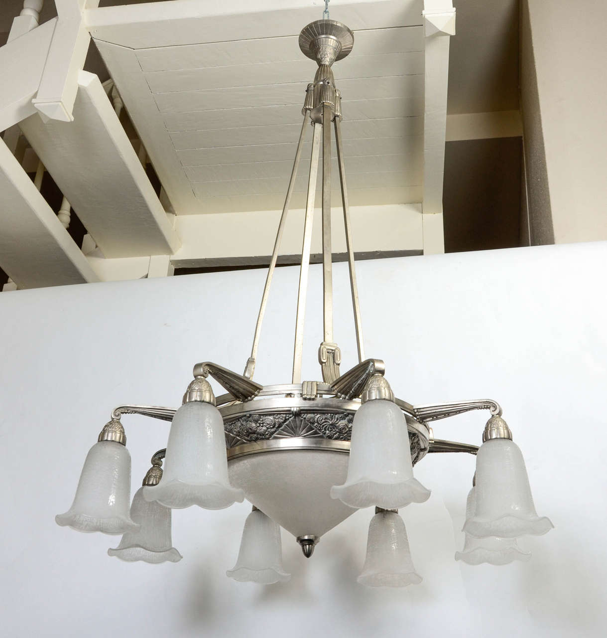 Important metal and glass chandelier, Daum, 1925.
High brushed steel structure with decorative flowers geometric design with eight lighting arms ended with white glass cups. Central glass cup. 
The glass pieces are signed 