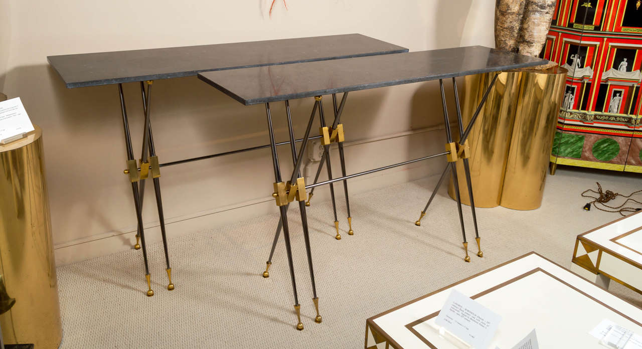A pair of rare consoles by LELEU Deocorateurs, in polished steel with gunmetal finish, gilt highlights and Belgian, black-granite tops.  France, circa 1962