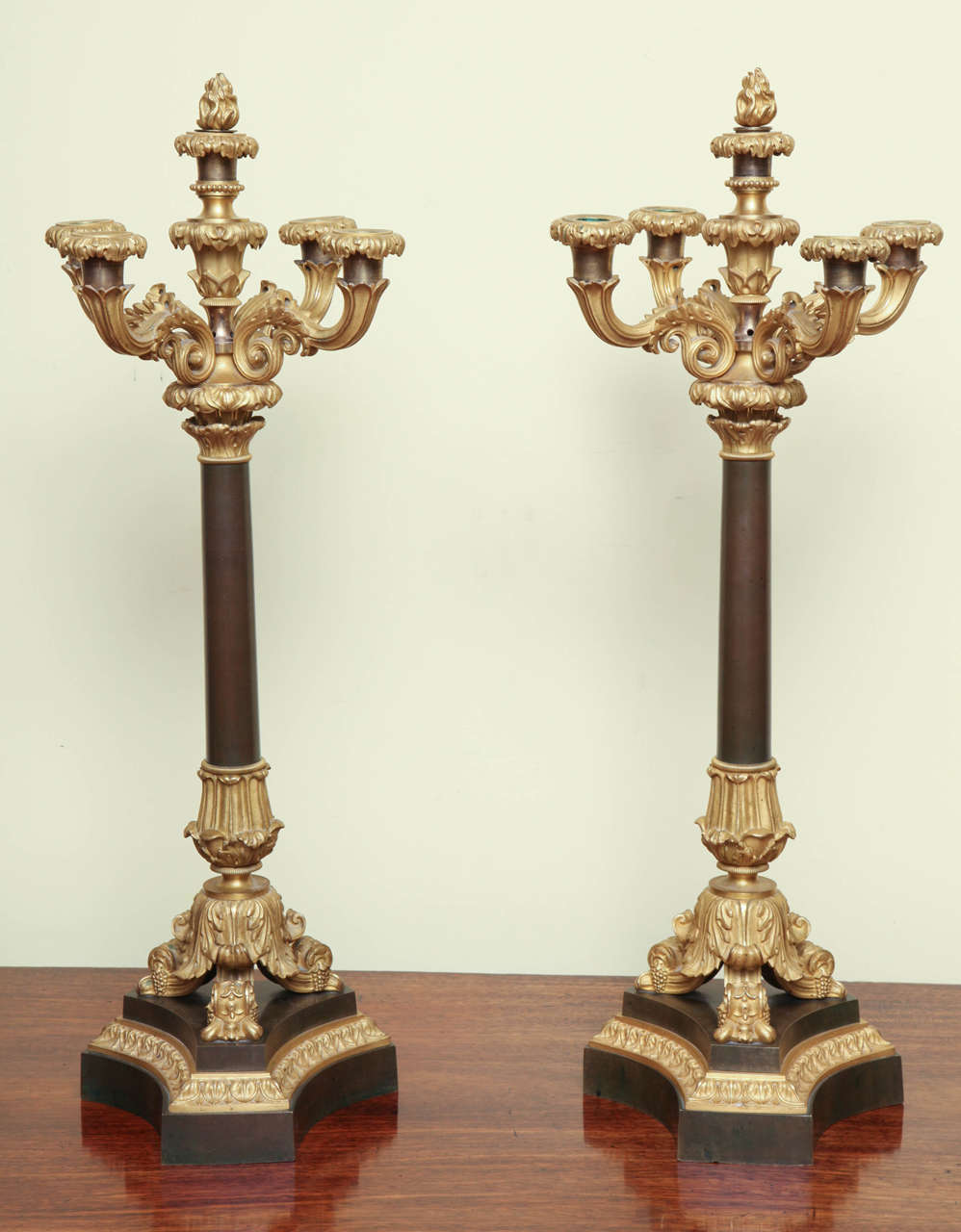 Fine Antique Pair of Louis Philippe Ormolu and Patinated Bronze five-light candelabra, having four scrolled ormolu candle arms surrounding a central raised shaft with a flame form finial which is removable to form the fifth candleholder, all