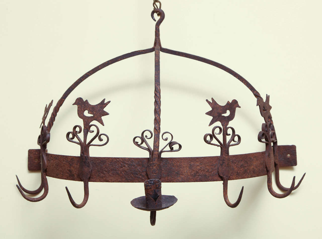 Fine pair of wrought iron flush-mounted rope twist supported game racks, each hemi-spherical in form, having a central curved candle arm with candle socket and drip pan flanked by six hooks, four of which are decorated with a silhouetted bird and