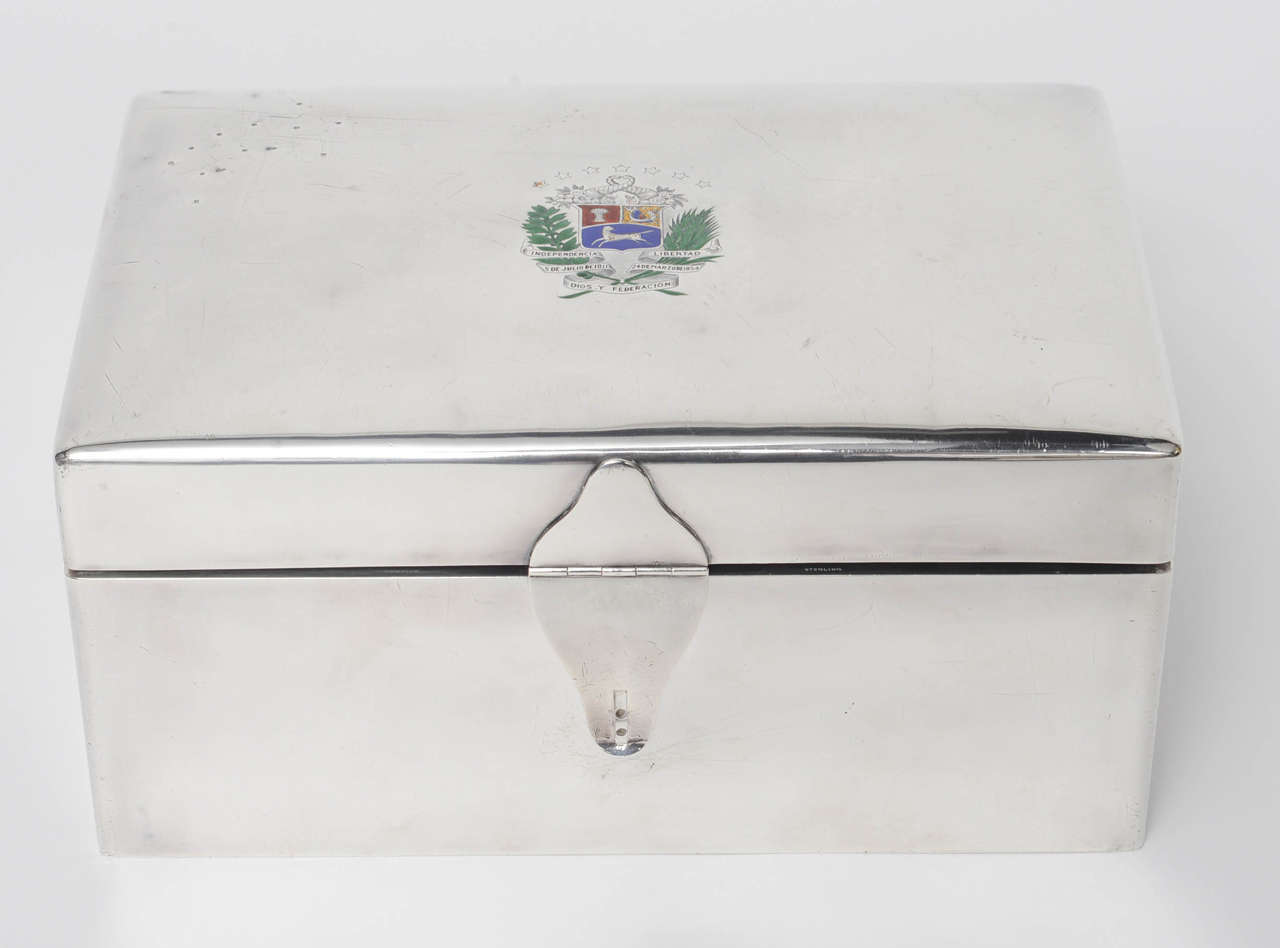 Rectangular box, the exterior applied with silver, gold and enamel insignia of the Venezuelan Republic, circa 1930, inside redlined in cedar wood and blue velvet. It was the property of the dictator of Venezuela, Juan Vicente Gomez for whom the box