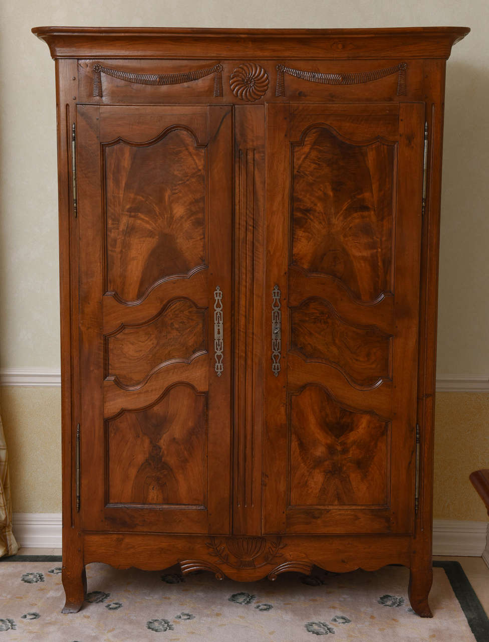 The frieze with fine carved swag decoration flanking a central rosette, over two-paneled doors opening to shelve, the deep scalloped apron centered by a fluted urn enclosed by laurel leaf fronds, on outward scrolling feet.