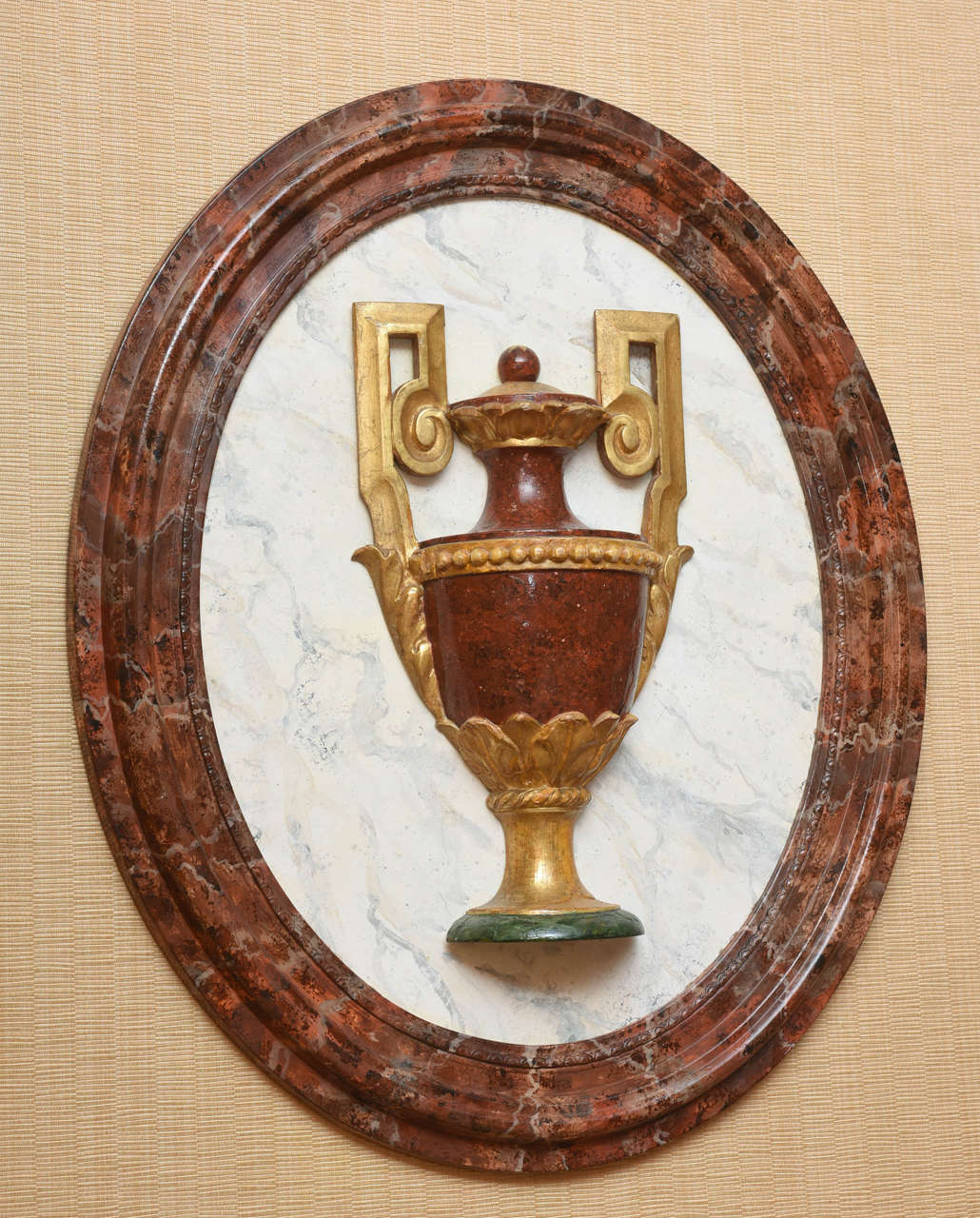 Beautifully painted in faux marbre; each oval plaque centered by a classical urn on a faux 