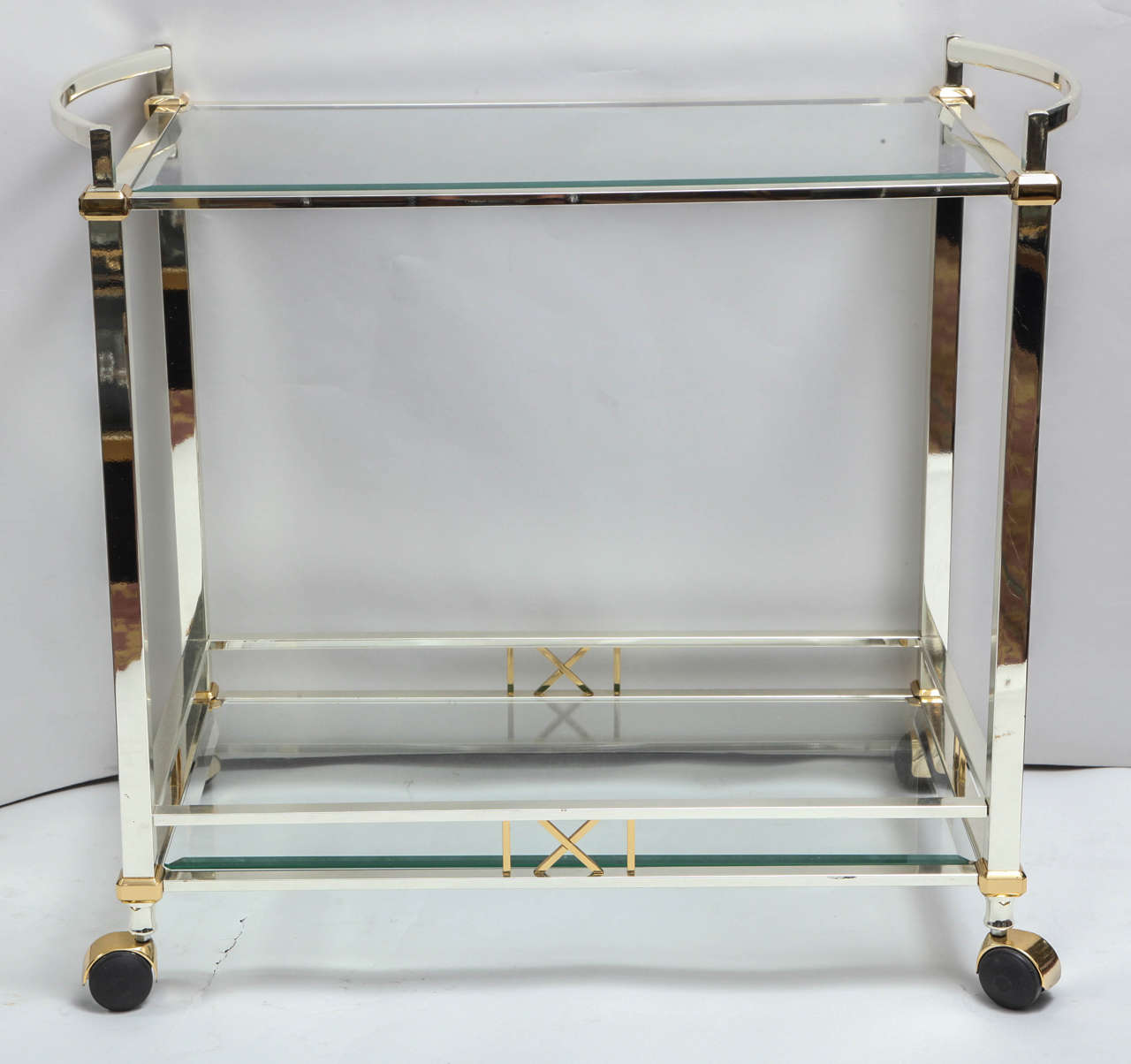 A sleek and stylish nickel-plated bar cart with brass details with two-tiered beveled glass shelves made by the Italian furniture company Orseniga. This highly functional cart is on great rolling casters and is able to fit in a modern interior