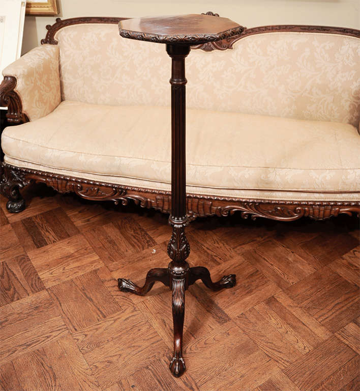 The octagonal top with a flowerhead-carved edge, above a fluted columnar standard with a leafy-urn base, all raised on cabriole tripod legs carved with acanthus at the knees and ending in ball and claw feet.