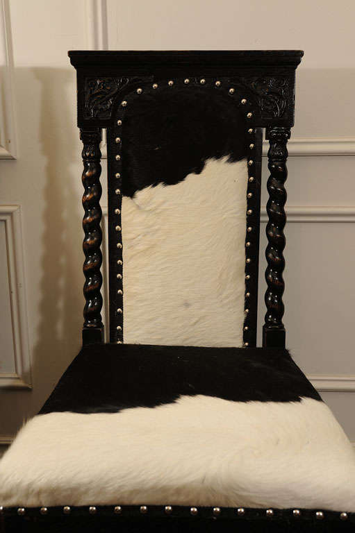 Austrian Pair of Black, Carved Chairs upholstered in Cow Hide For Sale