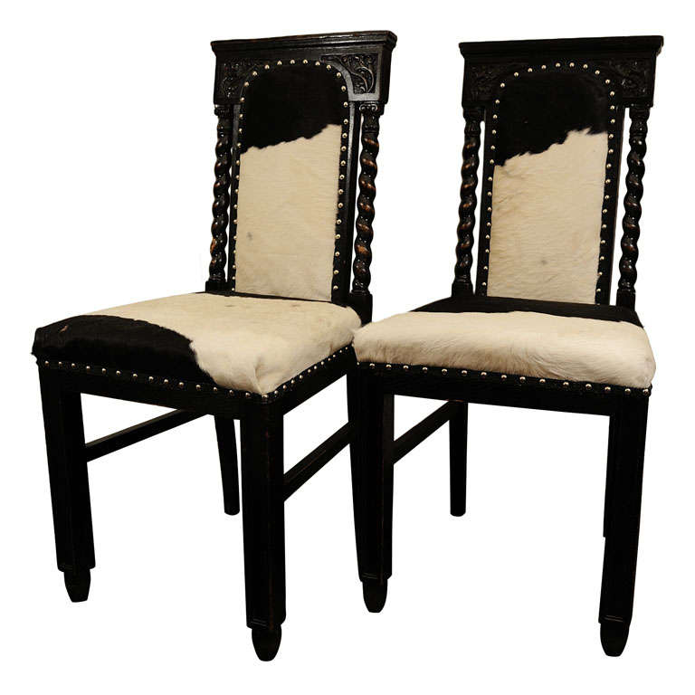 Pair of Black, Carved Chairs upholstered in Cow Hide For Sale