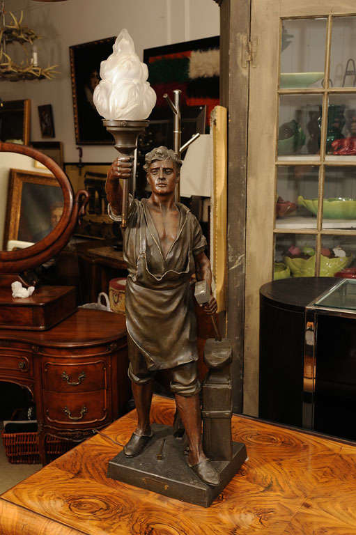Signed Sculpture of a Worker/lamp, carrying a torch, has a plaque-