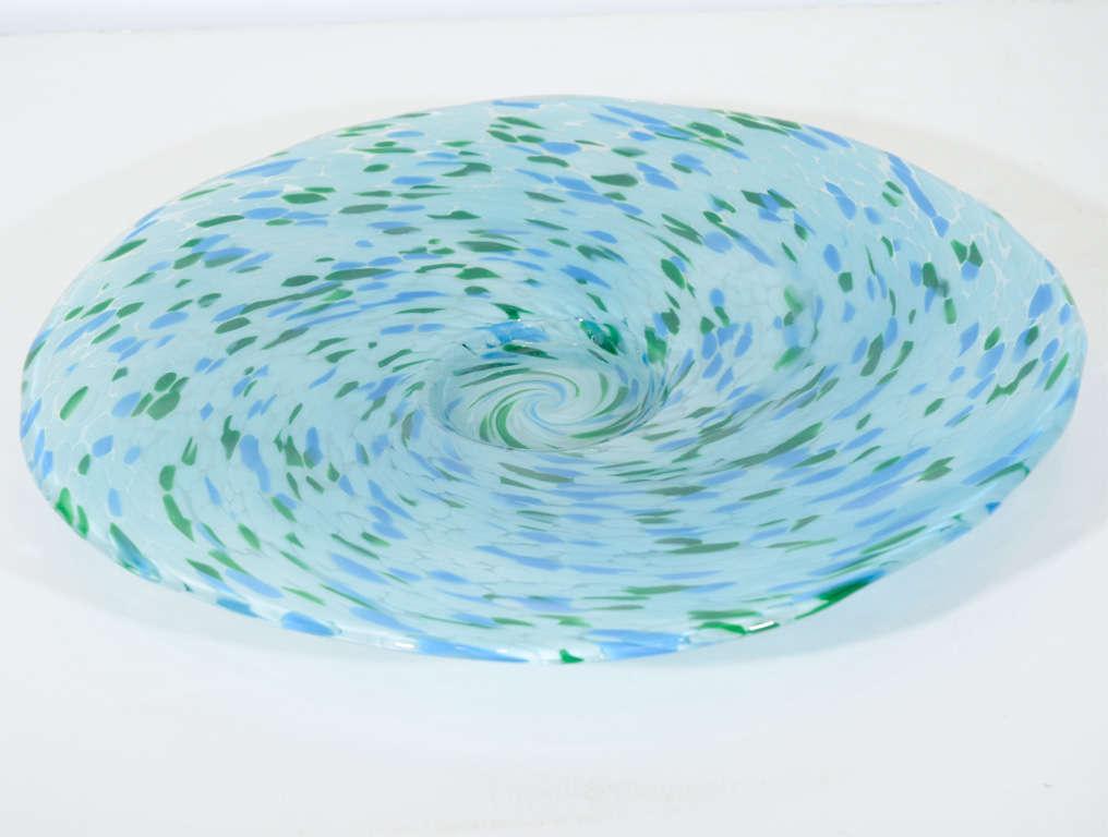 This stunning handblown Mid-Century Modernist features a rich swirling design of verdant green, Carolina blue and cream. This piece is both a functional plate and a stunning design object by itself that promises to add beauty and vibrant color to