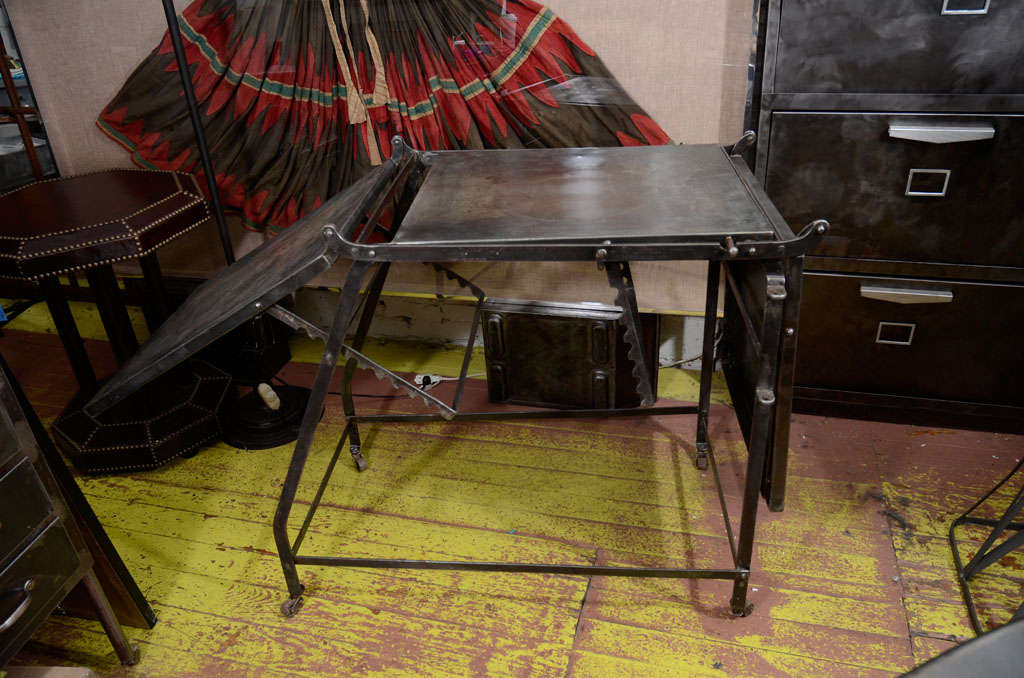Adjustable steel folding table, in three sections, with two hinged side-tables, on casters