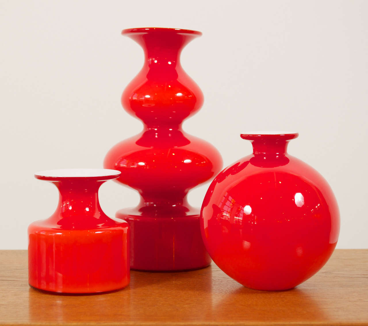 A grouping of curvy, red, carnaby vases of opal glass by Per Lütken and Michael Bang. Produced by Holmegaard.