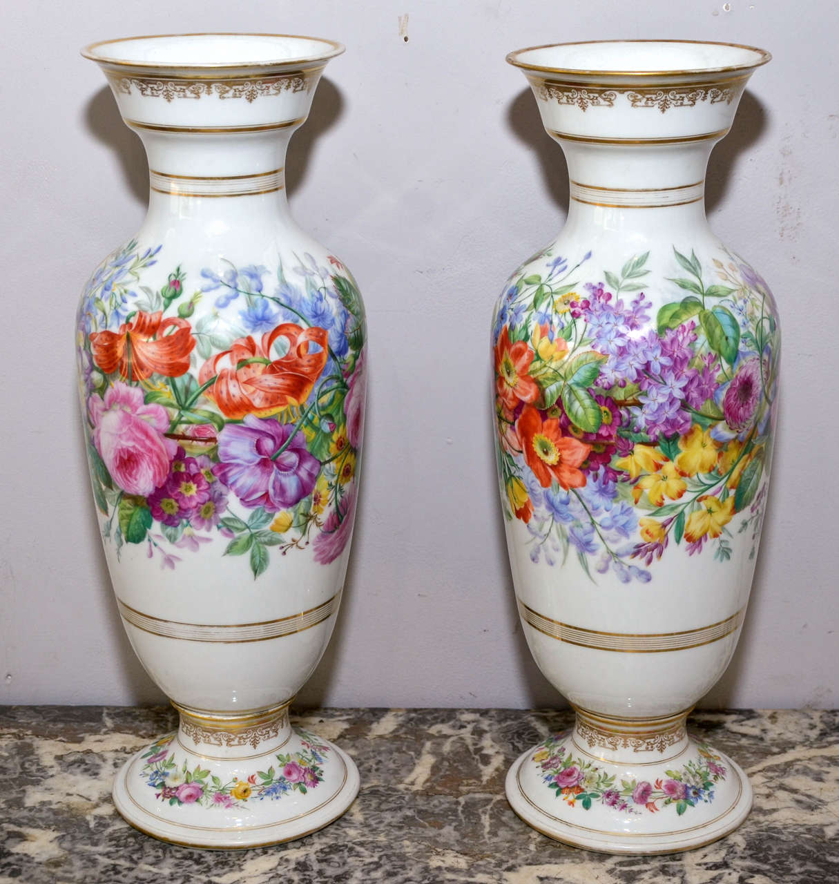 Two vases by Porcelaine de Paris, hand-painted with floral decor and gilded patina highlights.