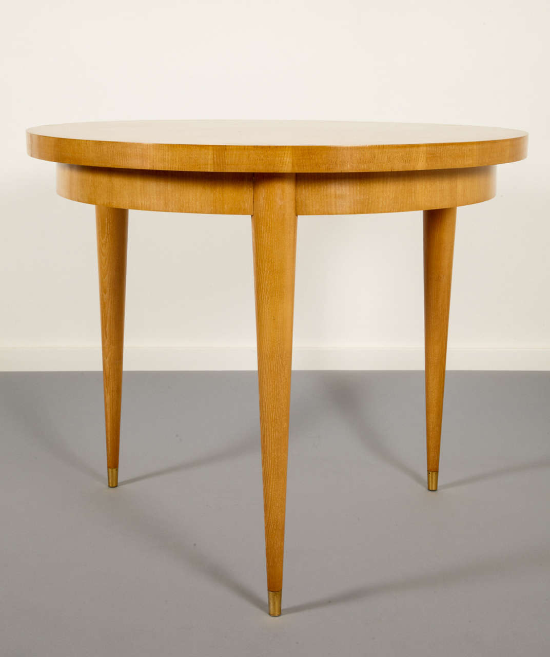 Circular massive oak table by Jean Royere, 1950s.  Regular belt Under top, resting on three conical feet with gilt brass sabots.
Prov. Apartment decorated by Mr Royère.
