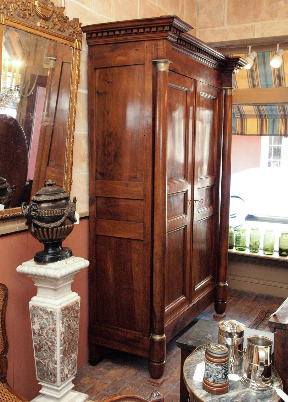 Fine early 19th century French Empire period walnut armoire with column corners, bronze mounts, and richly carved cornice.