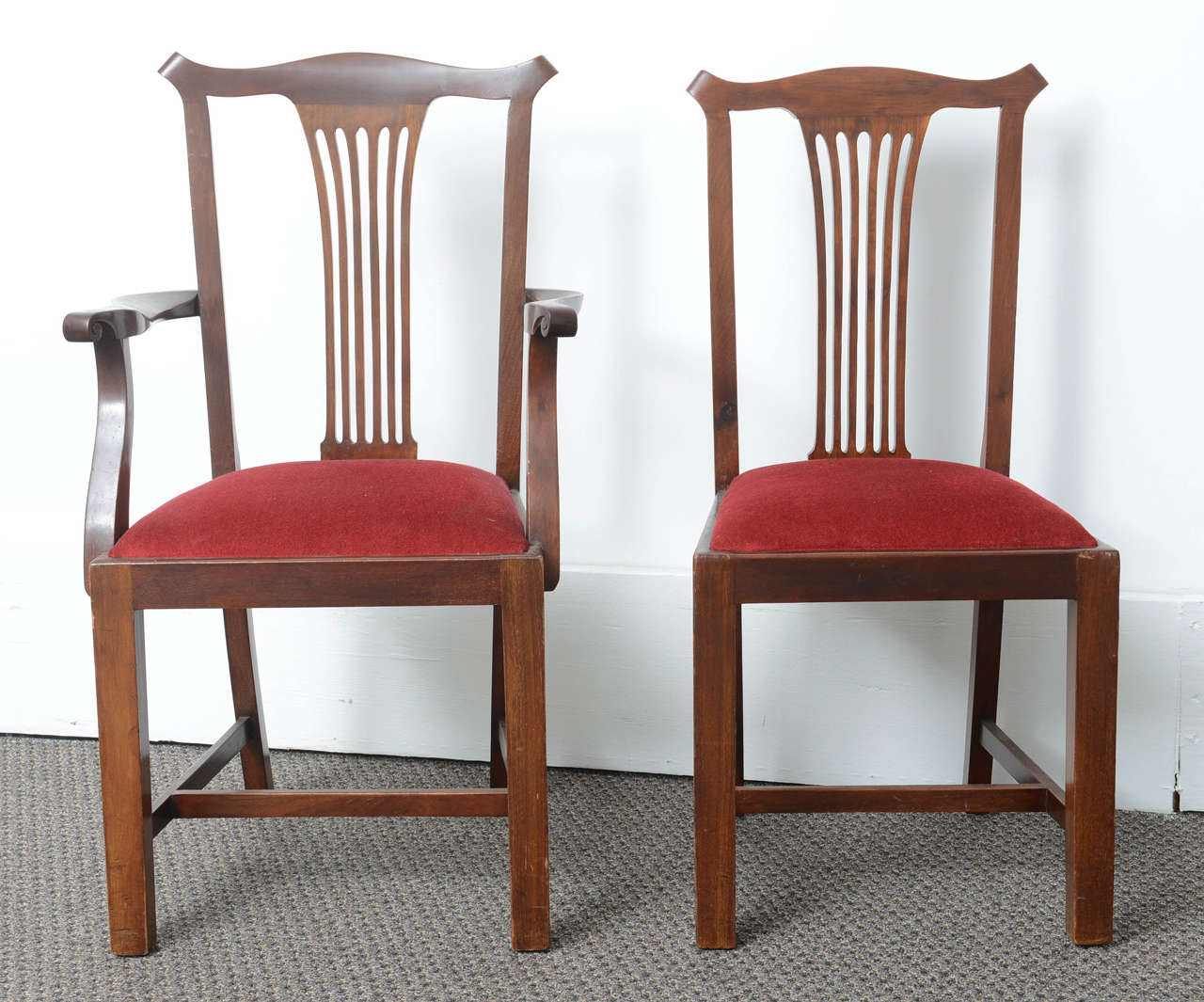 They are very nice set of eight dining chairs in mahogany made in England. They have a Hepplewhite style back and sit on square tapered legs. They have drop in seats which are recovered in red velvet and in good condition. To the legs they have