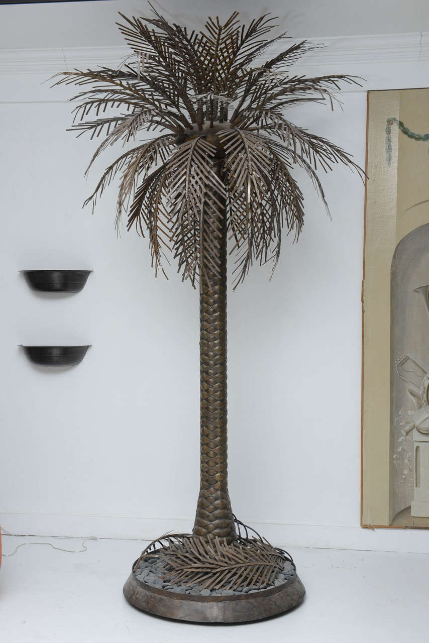 Iron sculptural Palm tree with textured trunk and removable leaves. The tree  leaves/ branches can be removed. Round base is filled with pebble stones for stability. There are three down lights inside of the tree crown, the tree is electrified.