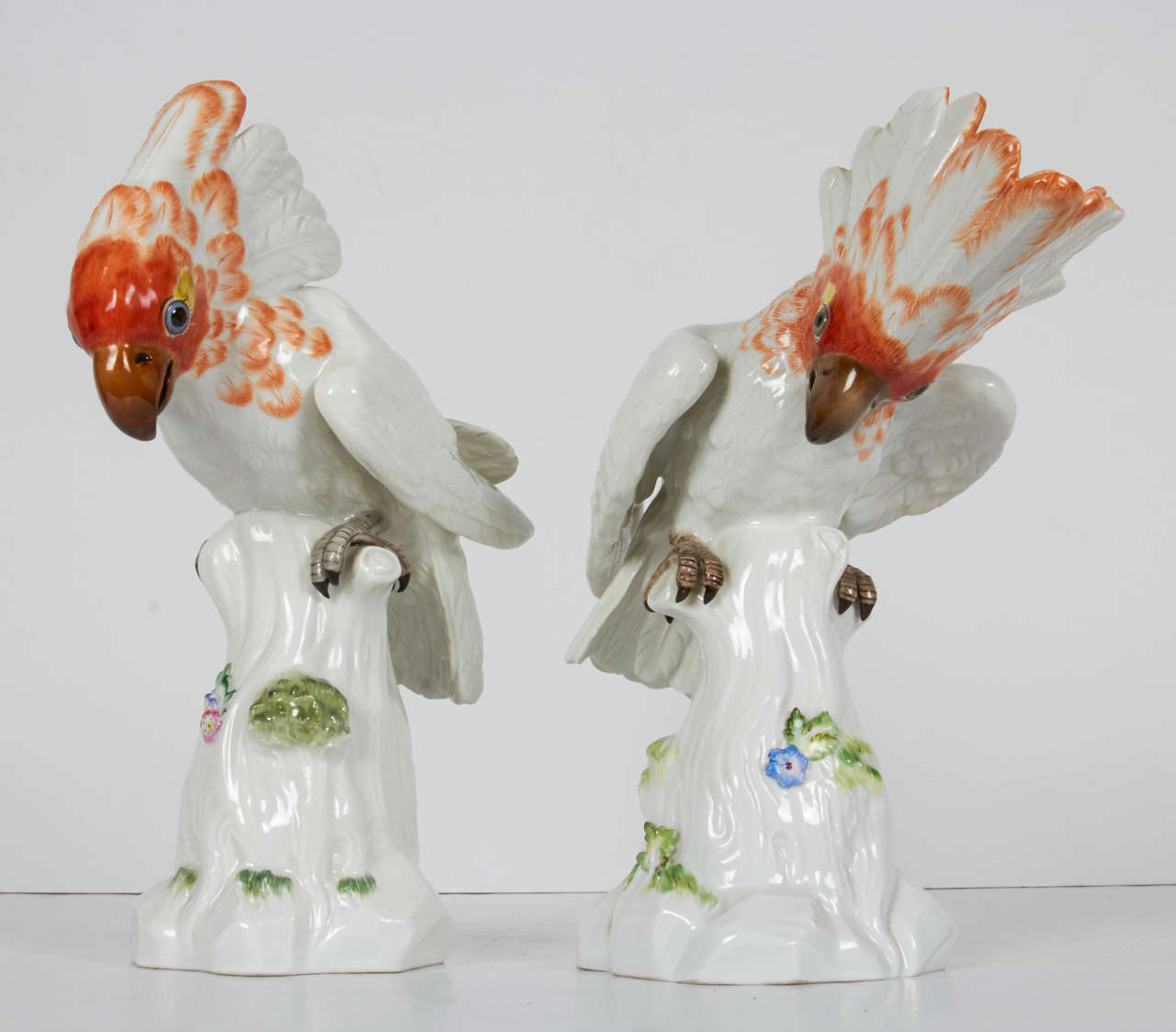 This fine pair of Meissen Porcelain figures of cockatoos / birds with orange feathers flared up, are perched on a tree with green leaves and small fine flowers. The cockatoos have very realistic features and colors. This original pair of porcelain