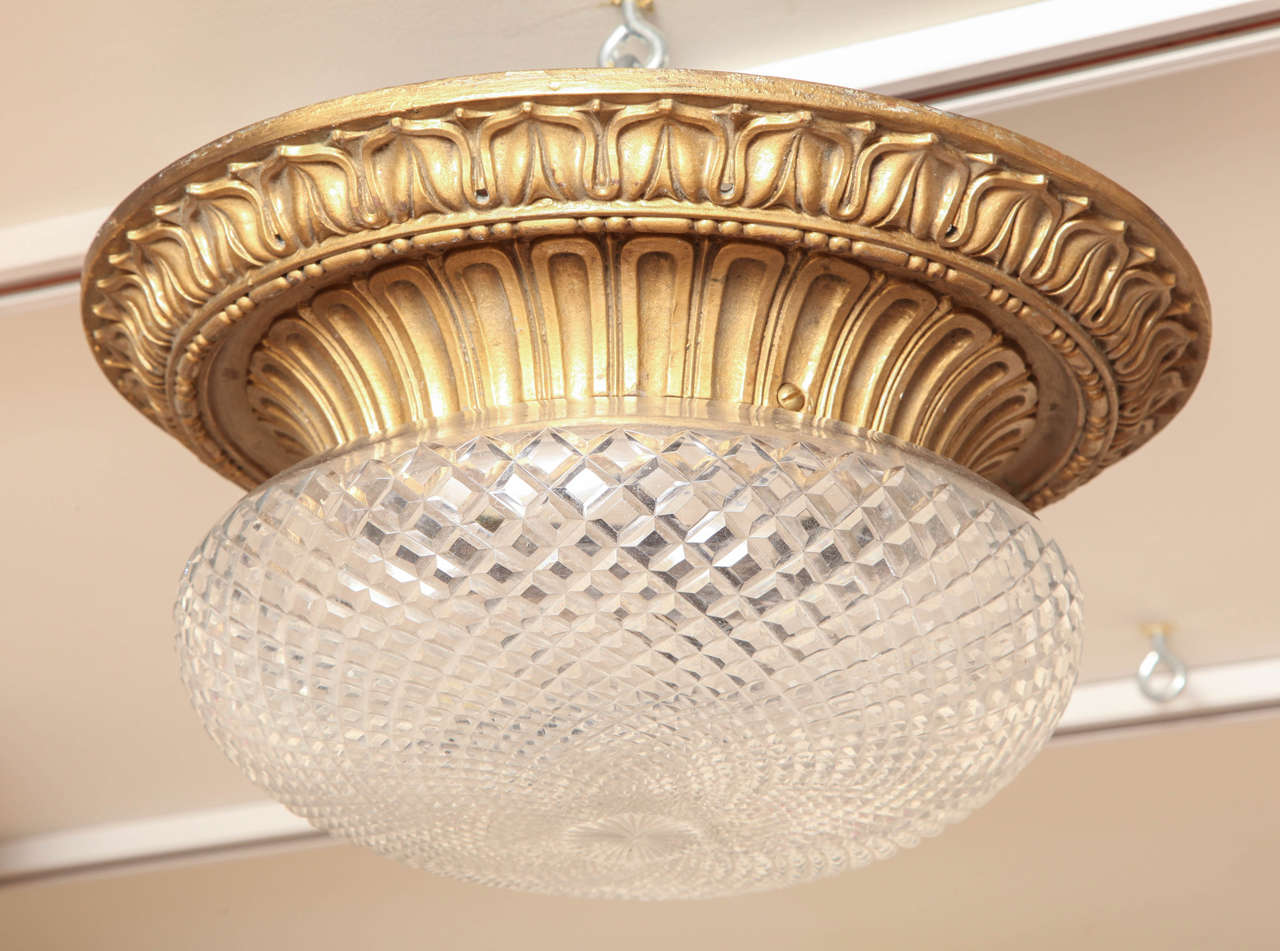 An American bronze flush mounted fixture by maker Caldwell. The round frame with leaf tip border surrounding arch fluted inner rim securing dome shaped cut glass shade with diamond pattern concealing 2 Edison sockets.