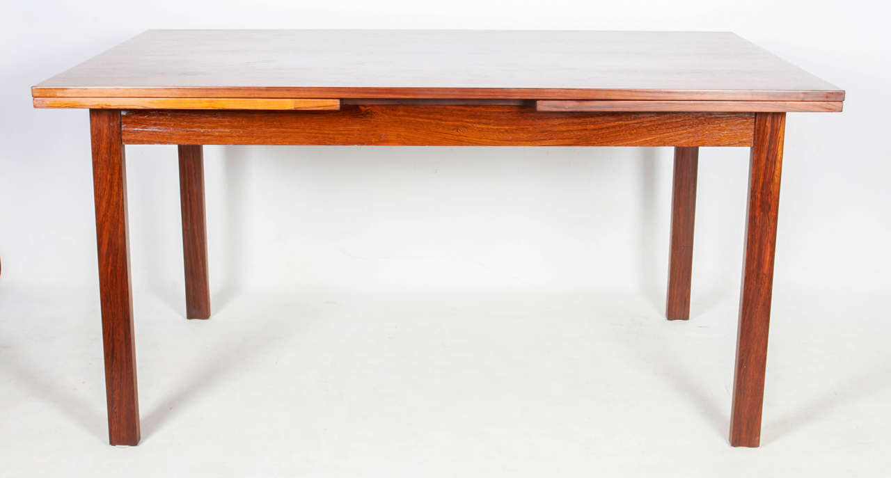 Architecturally designed modernist dining table in rosewood with bold rosewood graining. The table has two extensions: Each leaf measures 21.75 inches. Please contact for location. 