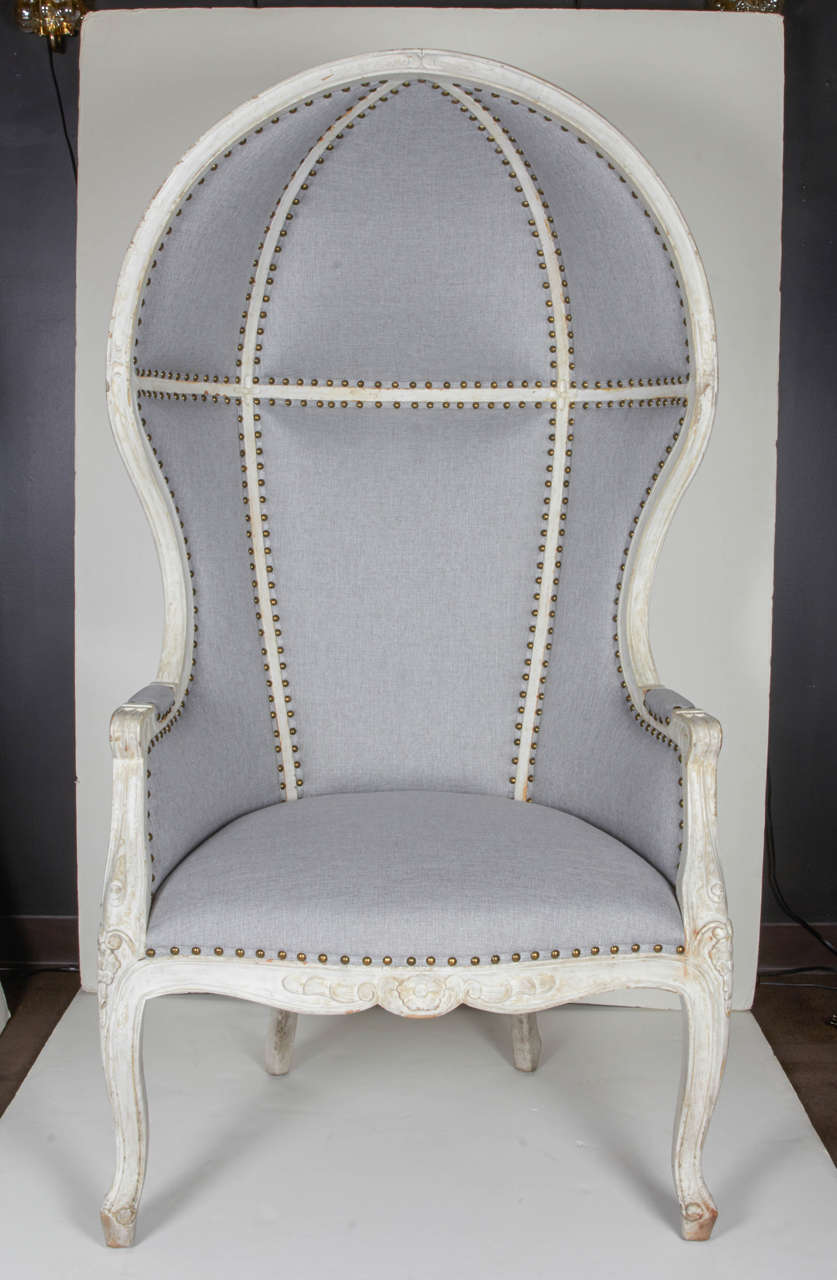 Pair of exceptional porter chairs with Louis XV/ Gustavian Era inspired design.
The chairs have tall, ultra-chic canopy tops with continual barrel back and winged sides. Carved wood frames in distressed white wash finish with ornate hand-carved