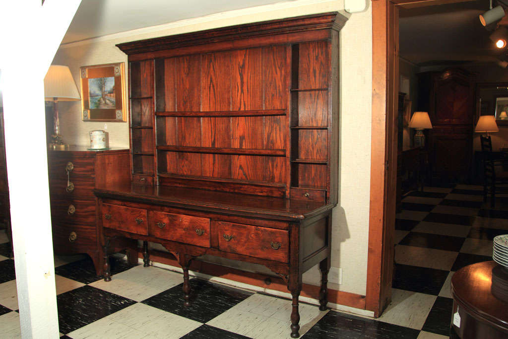 This oak and elm dresser from northern England shows an Irish influence in the fretwork corner brackets at the top of each well-turned leg. The juxtaposition of the centre and side shelves also create a visual interest that makes this dresser a