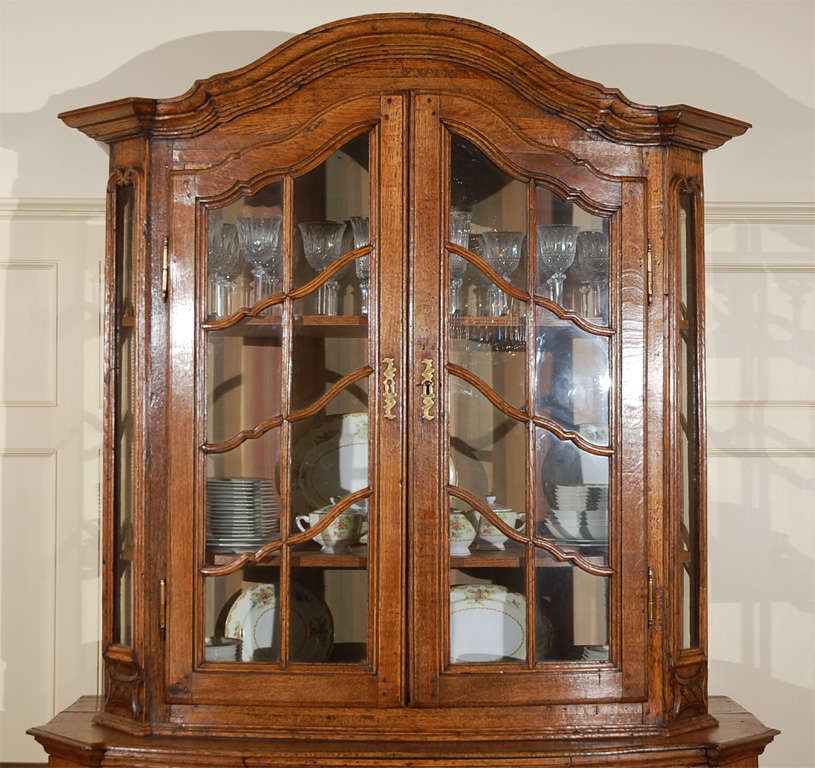 Antique Dutch hand carved and hand joined oak serpentine display cabinet with serpentine front. Glass on three sides of top. Beautifully crafted benchmade piece with small cupboard spaces at the sides of the bottom portion for trays and tall