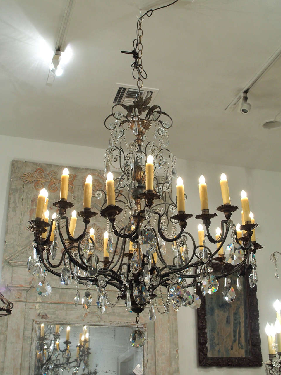 A large, handsome multi-light chandelier, likely produced in Spain, circa 1940 or 1950.  Having a soft, dark green painted finish with patinated gold tone repousse accents.  The crystals of a nice, hefty proportion and unusual shapes.  Swags of