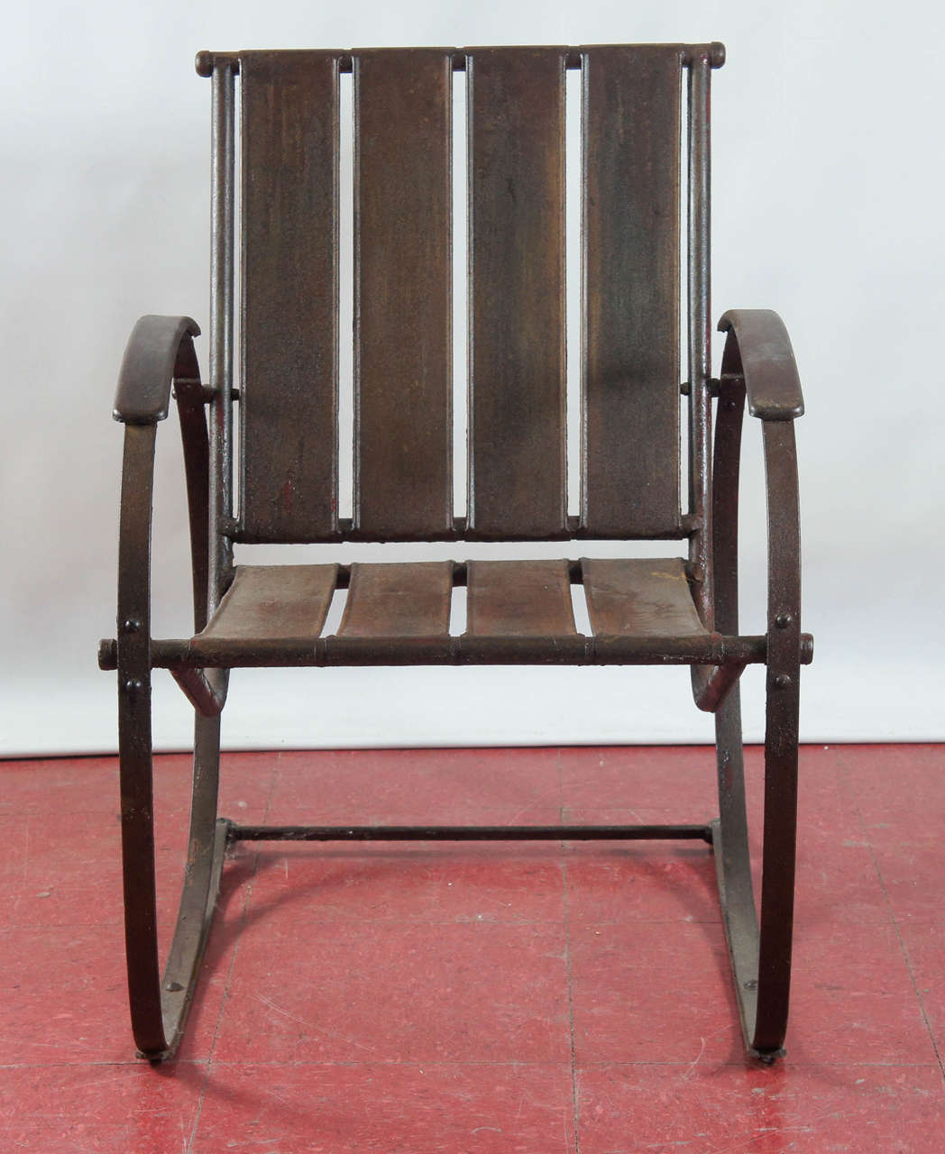 Sturdily constructed slatted iron garden chair has circular arms attached to stand-like base that can create a rocking motion for the sitter.

Arm height: 23.50