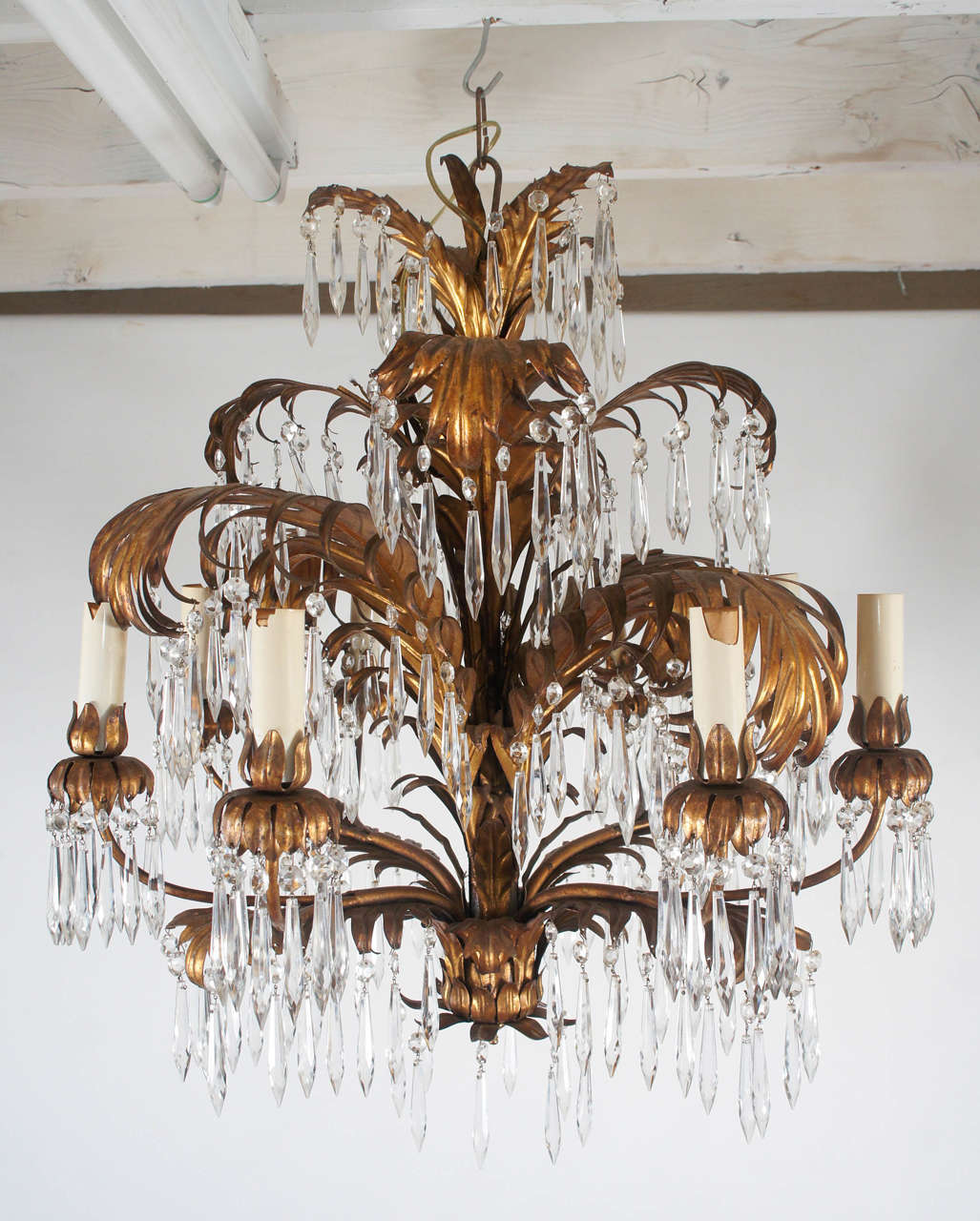 An elaborate Regency-Style chandelier composed of gilt metal palm leaves are  hung with many crystal drops.  Four pairs of lights are wired for US use.