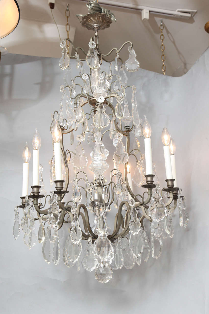 A nine light French Louis XVI style cage form chandelier with brushed nickel frame draped with crystals.