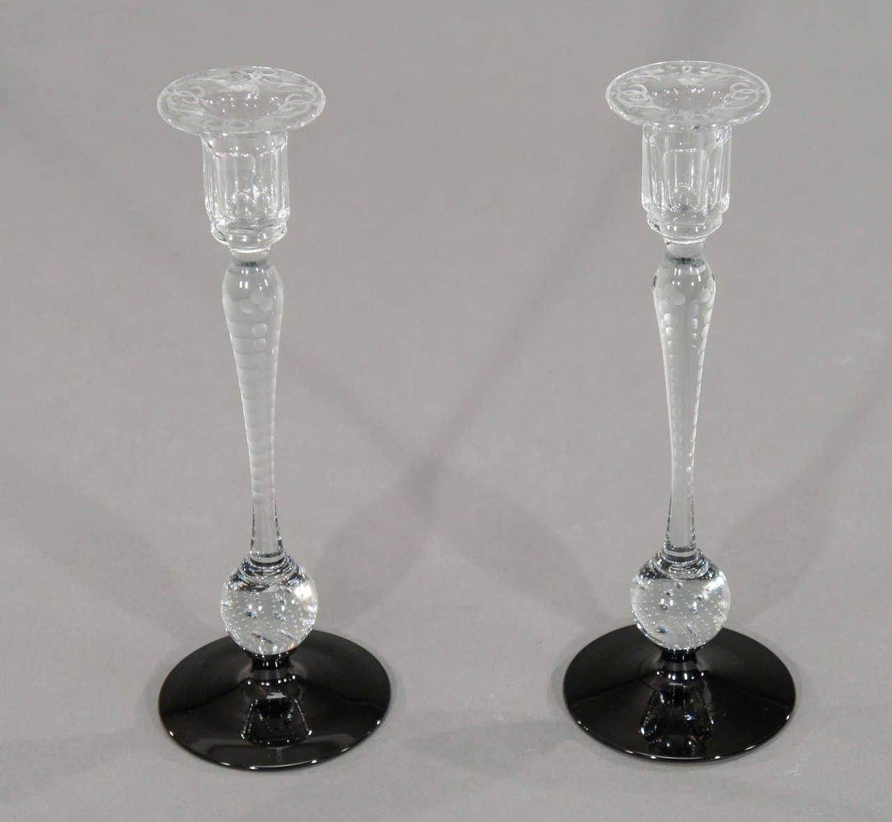 There are candlesticks and there is this pair!
Hand blown Pairpoint crystal stems with  controlled bubble connectors and a black base. Totally dramatic and to top it off, the bobeches and stems are wheel cut with a simple and elegant floral pattern.