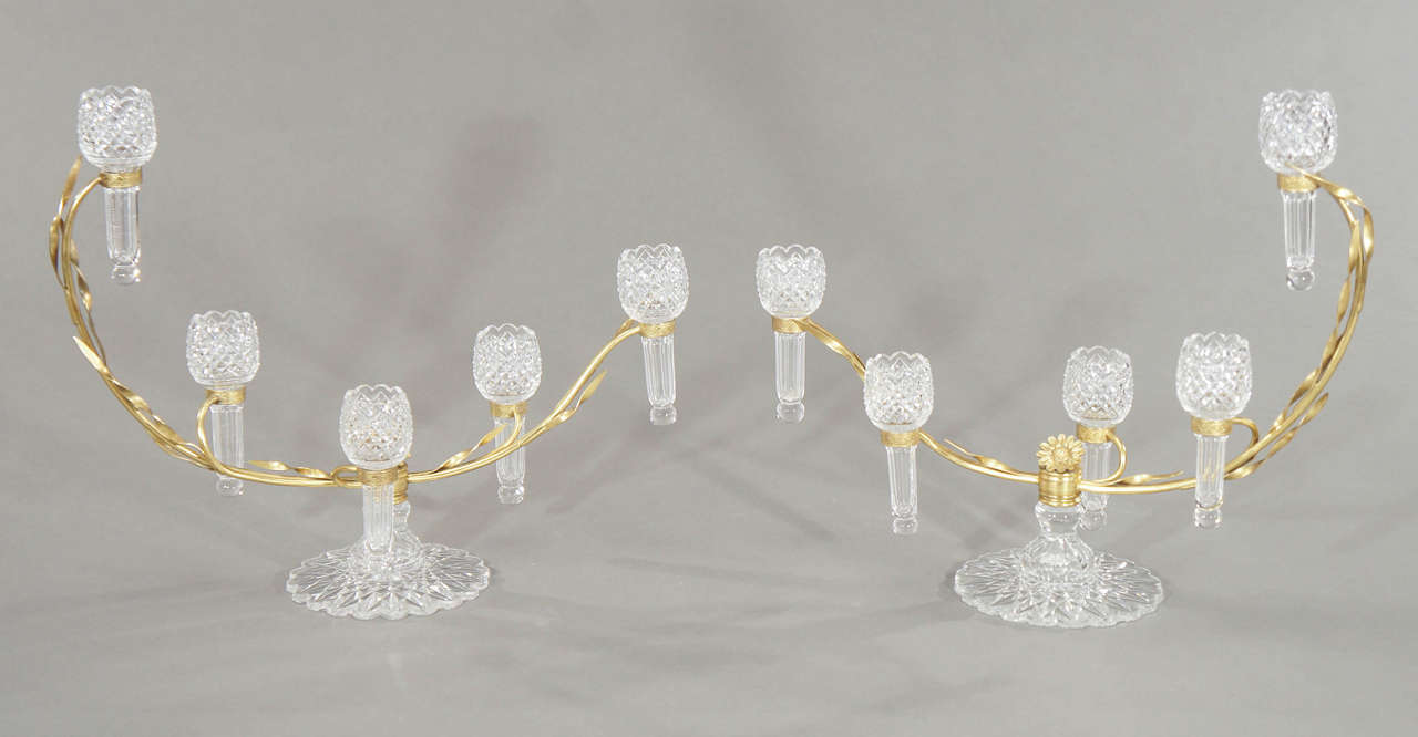 These matching epergnes are some of the best examples of the period. A rare matched pair of clear blown and cut glass epergnes, each with an arc shaped foliate mount holding 5 tulip-form vases. The crystal bases are elaborately cut in a diamond