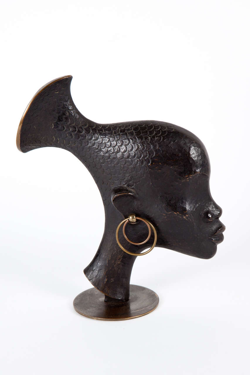 Karl Hagenauer bronze and patinated bronze African warrior head with a fish form.

stamped on the base.