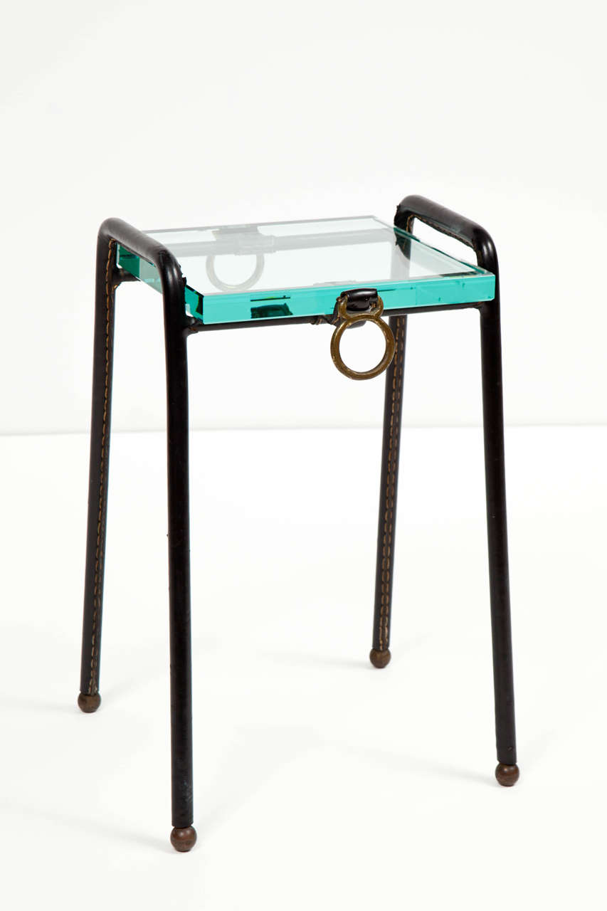 Jacques Adnet (1901-1984) catch-all side table with hand sewn saddle stitched black leather over steel, brass pulls, brass ball feet and thick glass top.