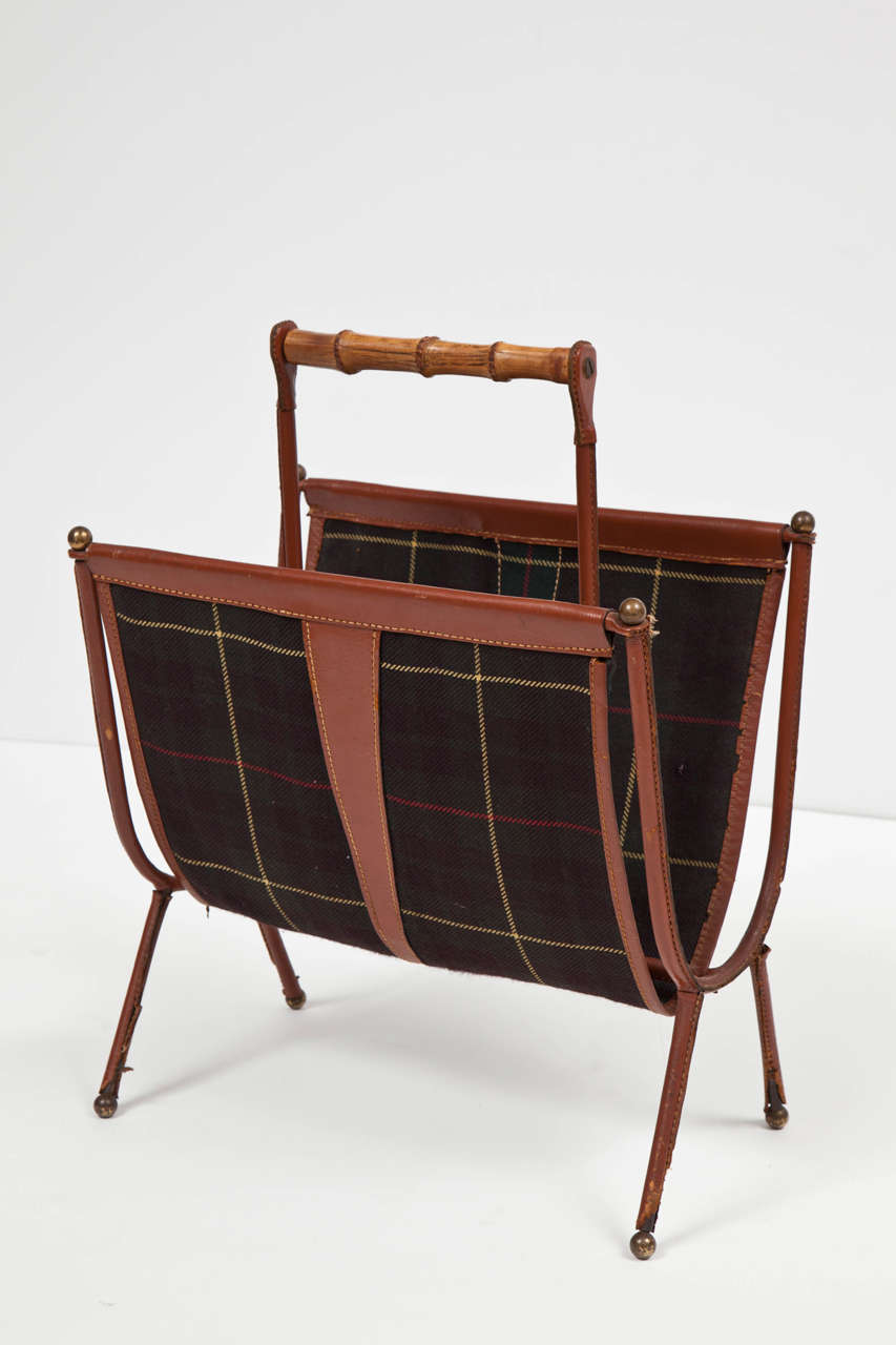 Magazine rack by Jacques Adnet (1901-1984) featuring original hand sewn saddle stitched brown leather over a steel frame with original plaid wool, bamboo wood handle and brass ball feet.

(Literature: Alain-René Hardy and Gaëlle Millet’s Jacques
