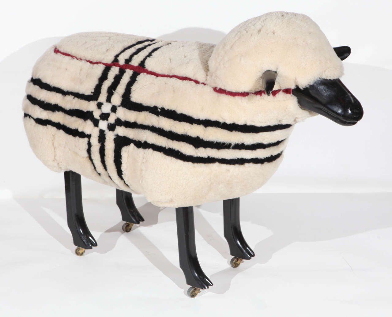 A unique Lalanne style sheep made for the Burberry store. Has the Burberry signature plaid stripes in black and burgundy. Has black lacquered wood ears, face and legs. Sculpture is set on four small casters.