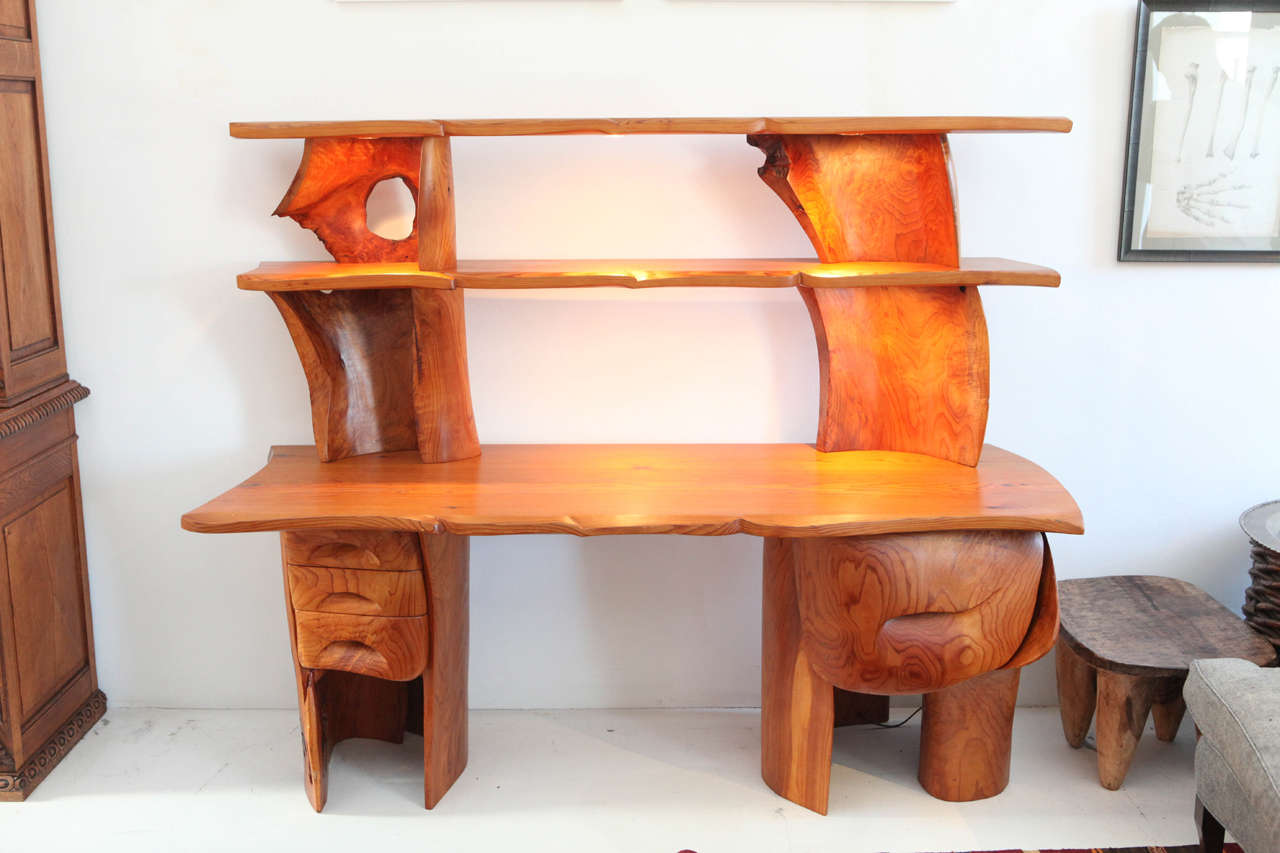 Commissioned sculptural desk from the 1970s in Red Cedar. Includes four drawers and six built in halogen lights on the shelves.