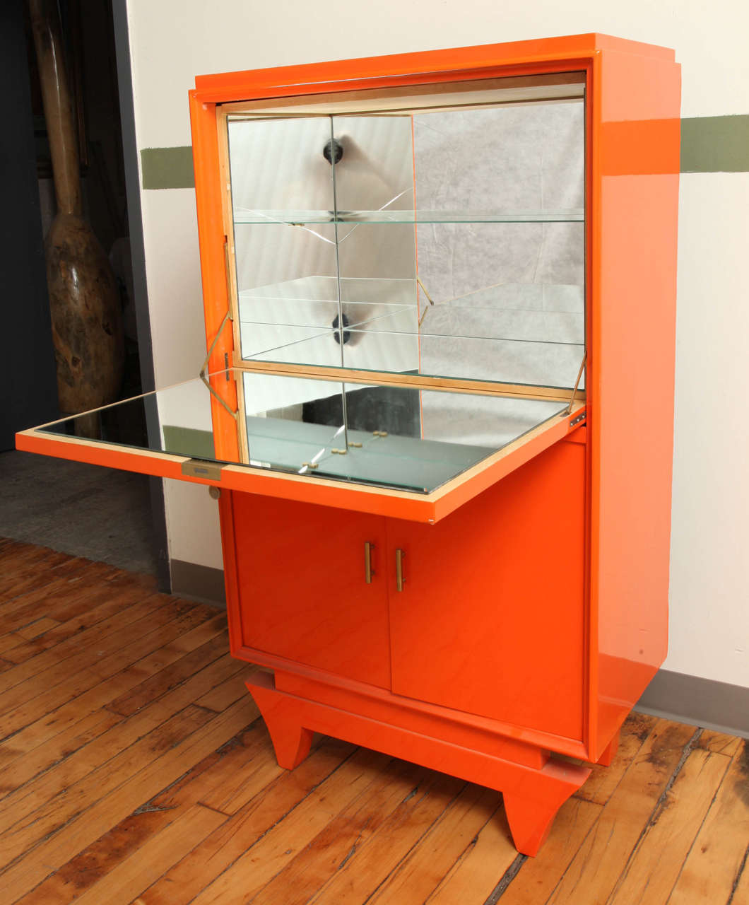 An Art Deco bar cabinet lacquered in Hermes orange with mirrored interior.