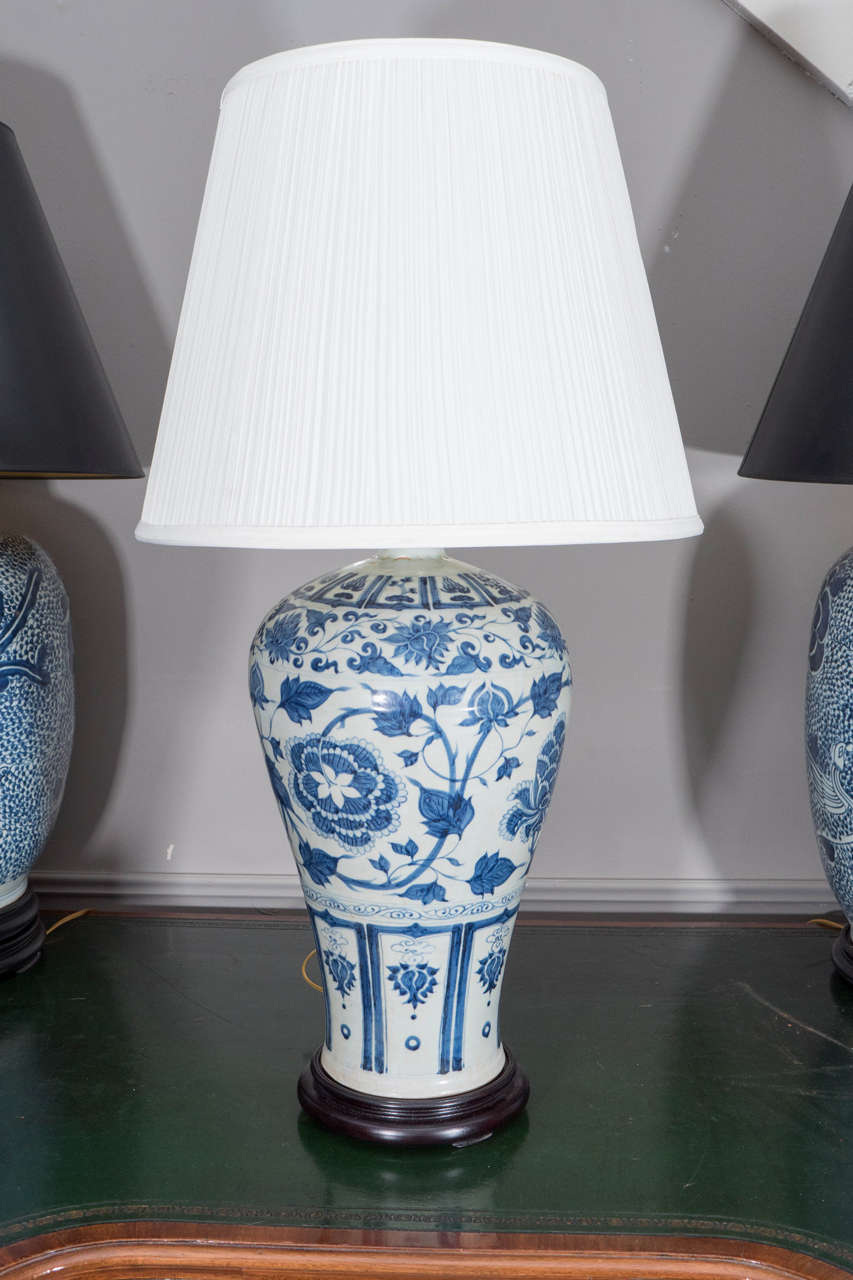 Pair of Chinese Blue and White Meiping Vases, Wired as Lamps. Ornamented with flowers, vines, and geometric motifs. On wooden bases. Shades available separately.

31" H (with harp)
18" H (to top of vase)
9 ½" Diam. (without shade)