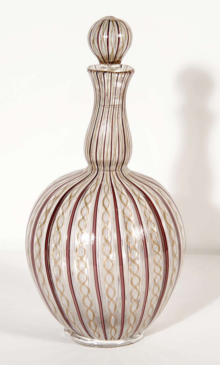 Zanfirico is a technique invented by glass makers on the Venetian island of Murano,Italy. Zanfirico glass consists of fine filagree canes which have been streched and twisted to form beautiful lattice patterns.This decanter features canes of 24k