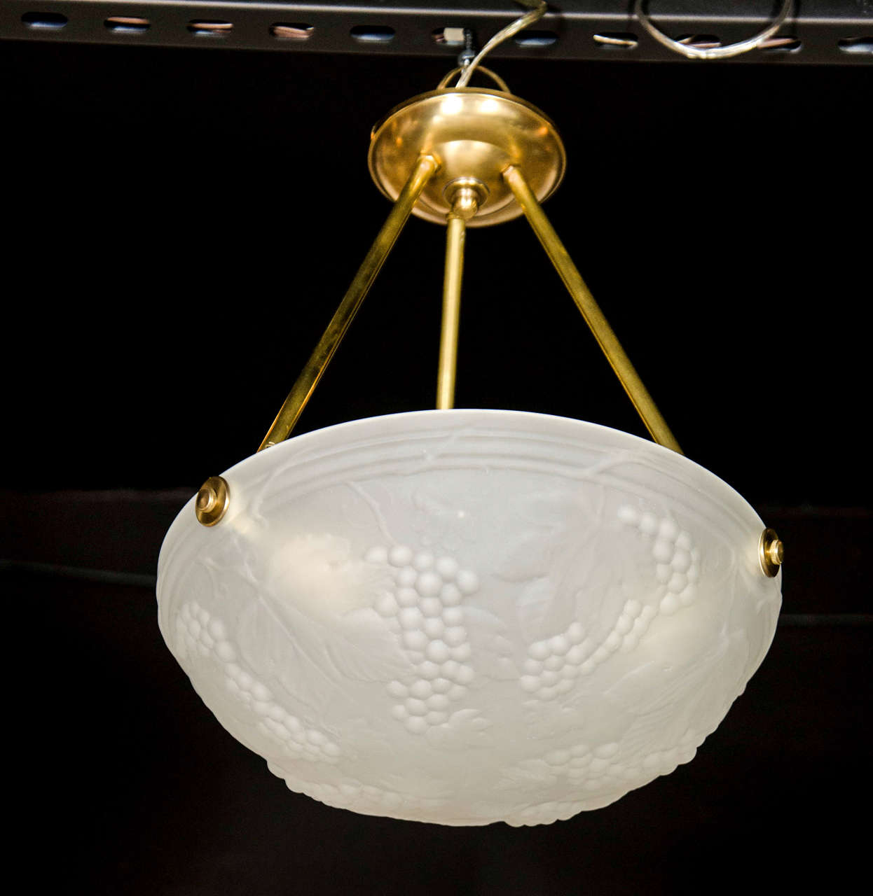 This elegant Art Deco flush mount chandelier features a frosted glass bowl shade with stylized grape and vine design with brass fittings. It is in excellent condition and has been newly rewired to American standards. The height can be adjusted to