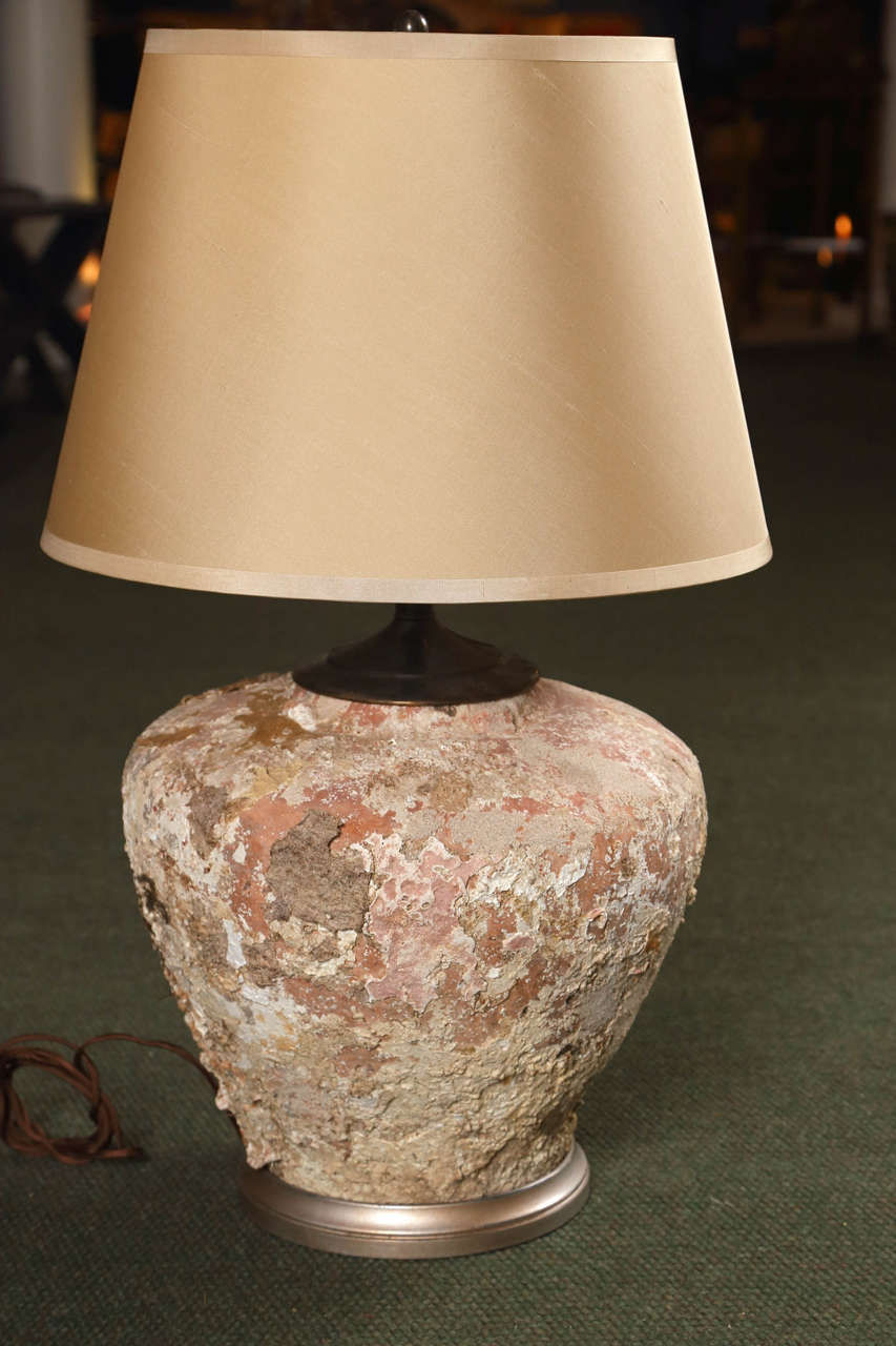 A pottery vessel with interesting shell encrustations converted into a lamp.