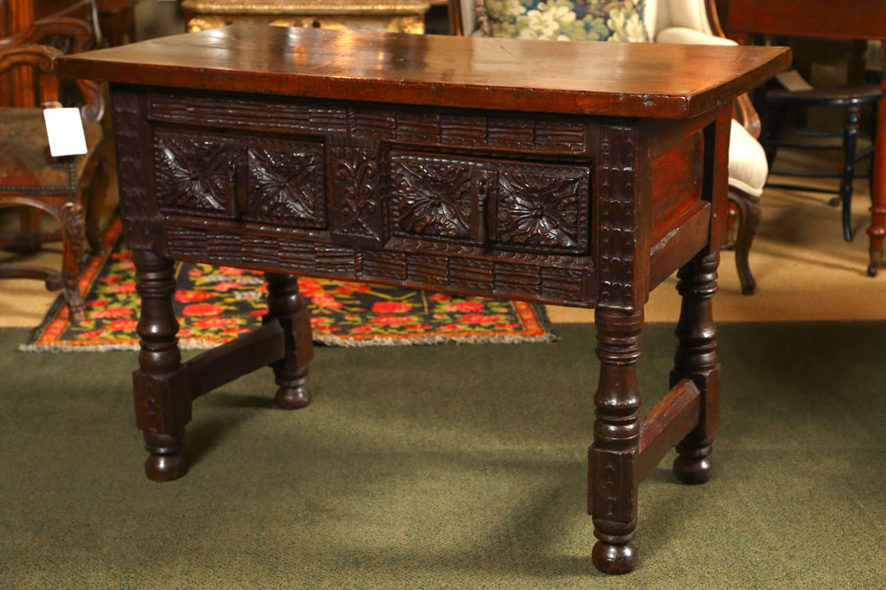 A carved two drawer Spanish table with a single walnut board top. In our opinion, this table displays some of the finest carving of the period.