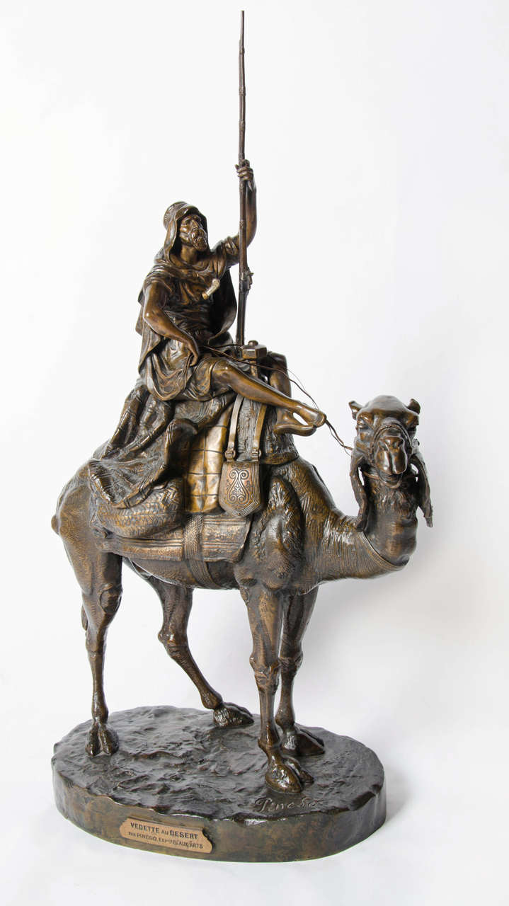 Vedette au Desert by Emile Pinedo (1840-1916), a gold and brown patinated bronze study of an Arab man riding his camel through the desert.  Stunning original condition. Set on a naturalistic integral plinth. Plaque to side inscribed Vedette au